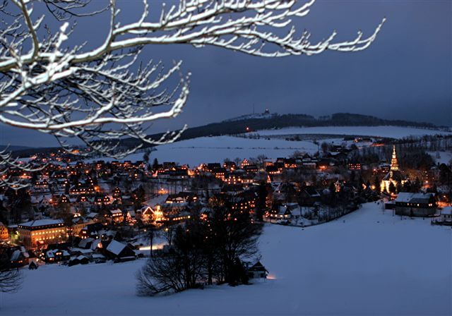 Blick vom winterlichen Schwartenberg auf das beleuchtete Spielzeugdorf Seiffen zur Weihnachtszeit